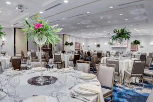 a banquet room with white tables and chairs and flowers at Doubletree by Hilton Harrisonburg in Harrisonburg