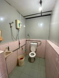 une salle de bains rose avec toilettes et lavabo. dans l'établissement Sri Sentosa Chalet, à l'Île Tioman