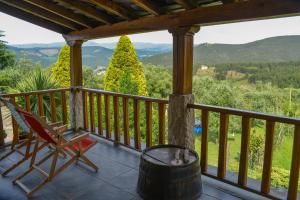 a porch with a chair and a barrel and mountains at Casa do Pinto in Arouca
