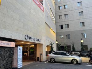 un coche plateado estacionado frente a un edificio en D'you Hotel, en Gwangju