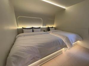 um quarto com 2 camas com lençóis brancos e luzes em D'you Hotel em Gwangju
