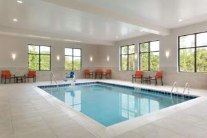 a pool in a hotel room with tables and chairs at Hampton Inn By Hilton North Olmsted Cleveland Airport in North Olmsted