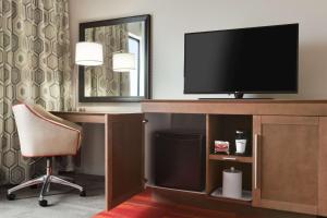 um quarto com uma secretária, uma televisão e uma cadeira em Hampton Inn By Hilton North Olmsted Cleveland Airport em North Olmsted