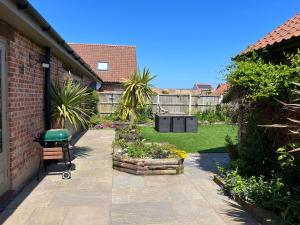 a backyard with a garden with a bench and plants at Honeysuckle Barn, Martham in Great Yarmouth