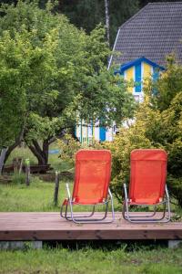 2 chaises rouges assises sur une terrasse en bois dans l'établissement Hot Tub with Wigwam Fluffy Horns - Kubls ar vigvamu Pūkainie Ragi, à Plieņciems