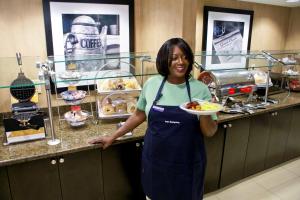 a woman in a kitchen holding a plate of food at Hampton Inn & Suites Charlotte-Airport in Charlotte