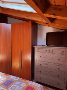um quarto com uma cama e uma cómoda com uma televisão de ecrã plano em Il nido di Arianna em Leggiuno