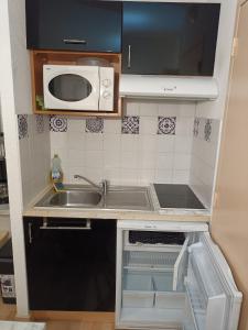 una pequeña cocina con fregadero y microondas en Guzet Neige 1400 en Ustou