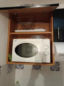 a white microwave in a cabinet in a kitchen at Guzet Neige 1400 in Ustou