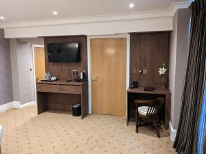 a hotel room with a desk and a television at The Tudor Hotel in Harrow