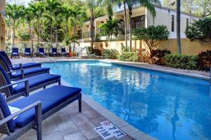 a large swimming pool with blue chairs and a building at Hampton Inn Miami-Coconut Grove/Coral Gables in Miami