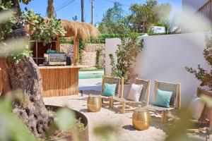 Mar Suites Formentera by Universal Beach Hotels في إس بوخولس: مجموعة من الكراسي مع الوسائد في الفناء