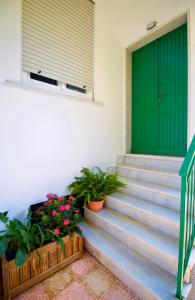 a green door on a house with flowers on the stairs at La casa dei nonni in Moneglia