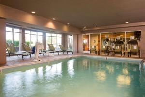 a swimming pool in a hotel with chairs and tables at Hilton Garden Inn Lexington in Lexington