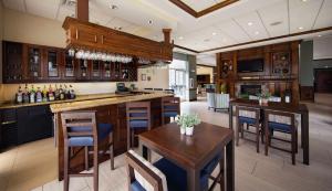 a kitchen with wooden cabinets and wooden tables and chairs at Hilton Garden Inn Valdosta in Valdosta