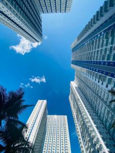 two tall buildings against a blue sky with a palm tree at CASA UNO By Mojo's Staycation in Manila
