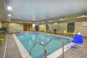a pool in a hotel room with chairs and tables at Home2 Suites By Hilton Carbondale in Carbondale