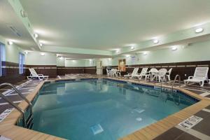 uma piscina num quarto de hotel com cadeiras e mesas em Homewood Suites Saint Cloud em Saint Cloud