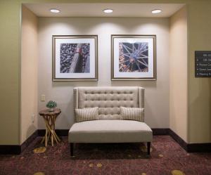 une chaise dans une salle d'attente avec deux photos sur le mur dans l'établissement Hilton Garden Inn Bentonville Rogers, à Bentonville