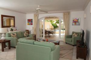 a living room with green couches and a dining room at Spinnaker, #127 Port St. Charles Marina, Speightstown - Waterfront Luxury in Saint Peter