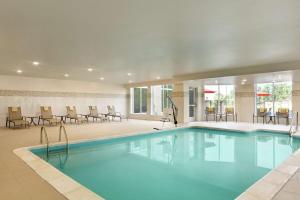 uma piscina num hotel com cadeiras e mesas em Hilton Garden Inn Statesville em Statesville
