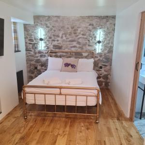 a bed in a room with a stone wall at Ness City Cottage in Inverness
