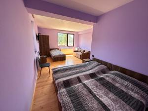 a bedroom with purple walls and a bed and a couch at House Near Forest in Bakuriani