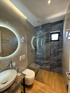 a bathroom with a toilet and a sink and a mirror at GL Hotel Ksamil in Ksamil
