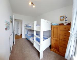 a bedroom with two bunk beds and a dresser at 9 The Downs, Thurlestone, South Devon on the coastal footpath overlooking Burgh Island in Thurlestone