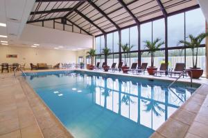 a large swimming pool with chairs and tables and windows at DoubleTree by Hilton Princeton in Princeton