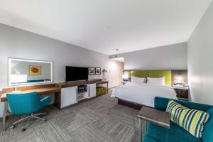 Cette chambre comprend un lit, un bureau et une télévision. dans l'établissement Hampton Inn & Suites Pryor, Ok, à Pryor
