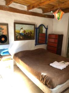 a bedroom with a large bed with paintings on the wall at REMODELAMOS casa sobre el rio a 100 mts del mercado municipal in Tilcara