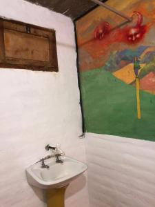un baño con lavabo y una pintura en la pared en REMODELAMOS casa sobre el rio a 100 mts del mercado municipal en Tilcara