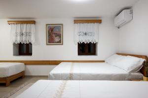 a bedroom with two beds and two windows at GUEST HOUSE ÇANI in Gjirokastër