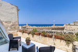 a balcony with chairs and a view of the ocean at Valletta Bastions Seafront House in Valletta