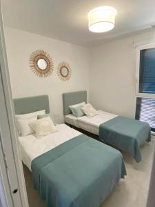 Pokój z 2 łóżkami i lustrem na ścianie w obiekcie Luxury Apartment Turquesa Del Mar w Alicante