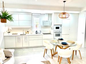 Luxury Apartment Turquesa Del Mar في أليكانتي: مطبخ مع دواليب بيضاء وطاولة وكراسي