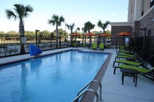 una gran piscina con mesas y sillas verdes en Hampton Inn and Suites Missouri City, en Missouri City