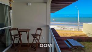 een balkon met 2 stoelen en een tafel en uitzicht op het strand bij Qavi - Flat em Pirangi Living #PirangiChalé13 in Parnamirim