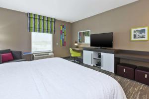 a hotel room with a bed and a flat screen tv at Hampton Inn Sedalia in Sedalia