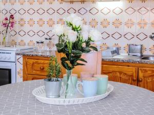 une table avec des tasses et un vase avec des roses blanches dans l'établissement Live Tenerife La Barranquera con vistas al mar, à Valle de Guerra