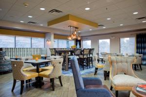 a restaurant with tables and chairs and windows at Hampton Inn Milledgeville in Milledgeville