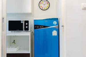 a refrigerator with a microwave and a clock on a wall at Baan Koo Kiang Hua Hin คอนโดบ้านคู่เคียง หัวหิน in Hua Hin