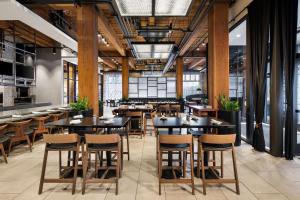 ミネアポリスにあるCanopy by Hilton Minneapolis Mill Districtの木製のテーブルと椅子と窓のあるレストラン
