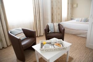 une chambre d'hôtel avec deux chaises, une table et un lit dans l'établissement Hotel Autre Mer, à Noirmoutier-en-l'lle
