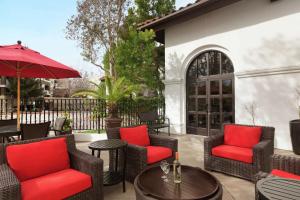 un patio con sillas, una mesa y una sombrilla en Hilton Garden Inn Cupertino, en Cupertino