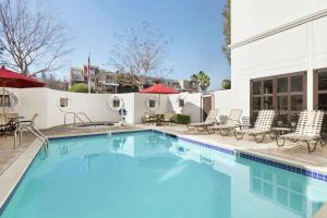 a swimming pool with chairs and tables and a building at Hilton Garden Inn Cupertino in Cupertino