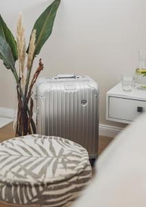 a silver suitcase sitting next to a chair and a plant at Hotel Caraleon in Wasserburg am Bodensee