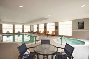シャーロッツヴィルにあるHomewood Suites by Hilton - Charlottesvilleのプール、テーブル、椅子が備わるホテルルームです。