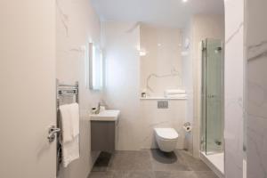 a white bathroom with a toilet and a sink at Tower Residences by Blue Orchid in London